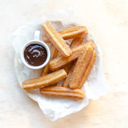 churros in a bowl with a side of chocolate sauce