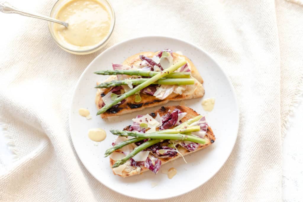 radicchio caesar toast with asparagus on a round plate