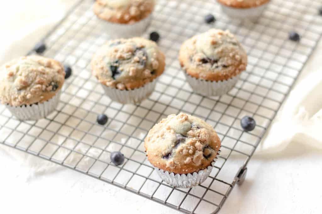 Blueberry cherry muffins on a cooling rack with scattered blueberries