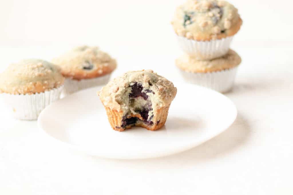 Blueberry muffin on a white round plate with a bite taken out of it