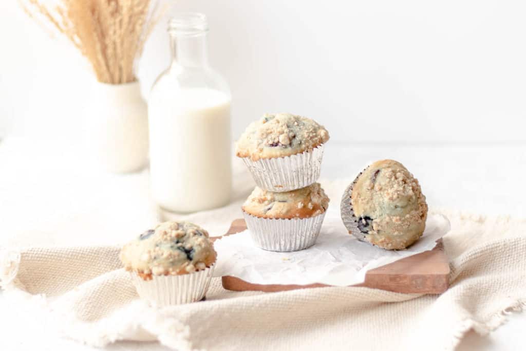 blueberry cherry muffins stacked on a cutting board with a glass of milk