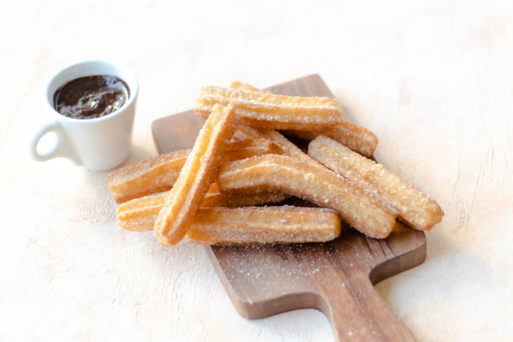 cinnamon churros piled on a cutting board