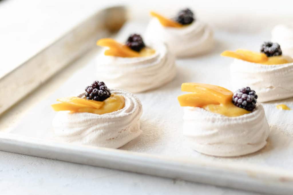 mini pavlovas with lemon curd and blueberry on a sheet tray