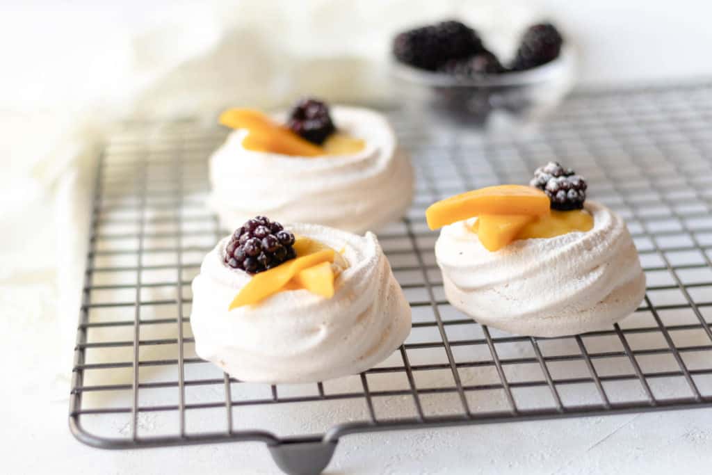mini pavlovas on a cooling rack with blueberries