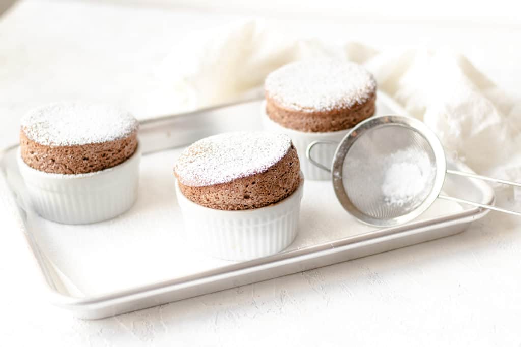 chocolate soufflé on baking dish with strainer and topped with powdered sugar