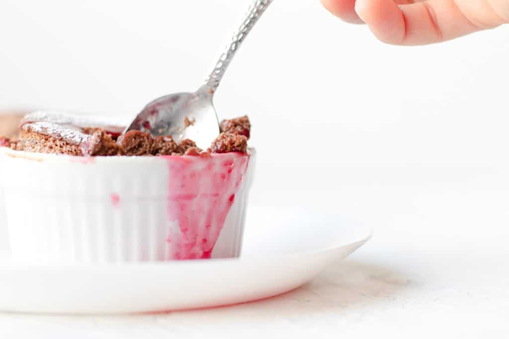 spoon being inserted into chocolate soufflé ramekin