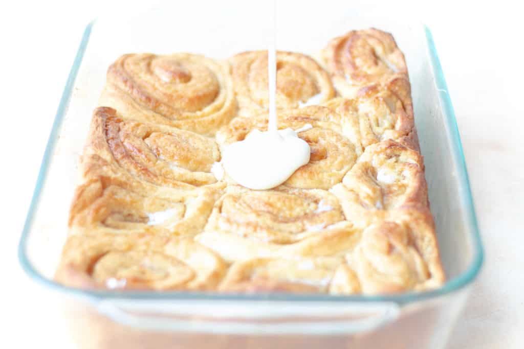 cinnamon rolls with cream cheese frosting being poured on top