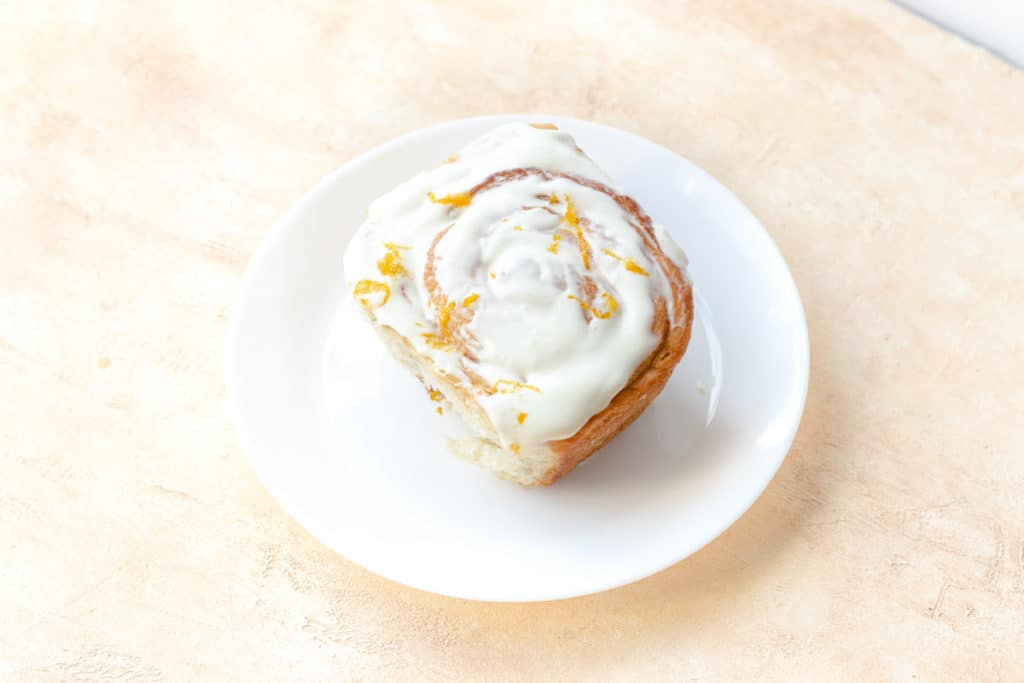 cinnamon roll with orange and cream cheese icing on top
