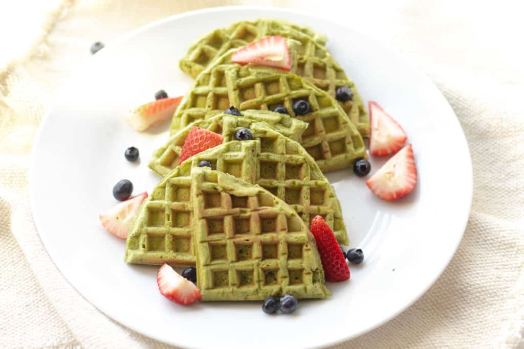 matcha waffles on a plate with strawberries and blueberries 