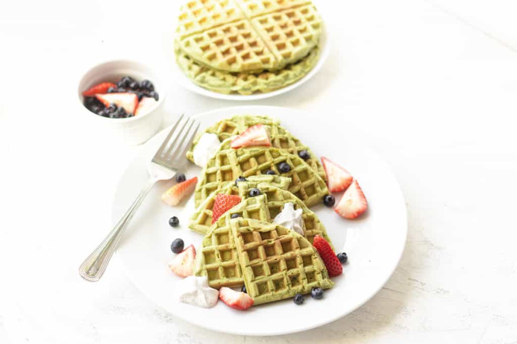 matcha waffles on a plate with a side of fruit