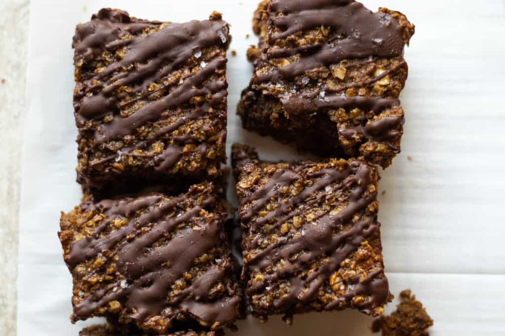 close up shot of chocolate drizzled oat bars sprinkled with flaky sea salt