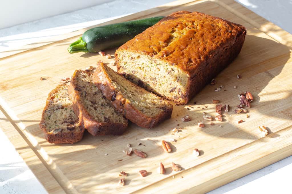 zucchini bread sliced on a cutting board with pecans