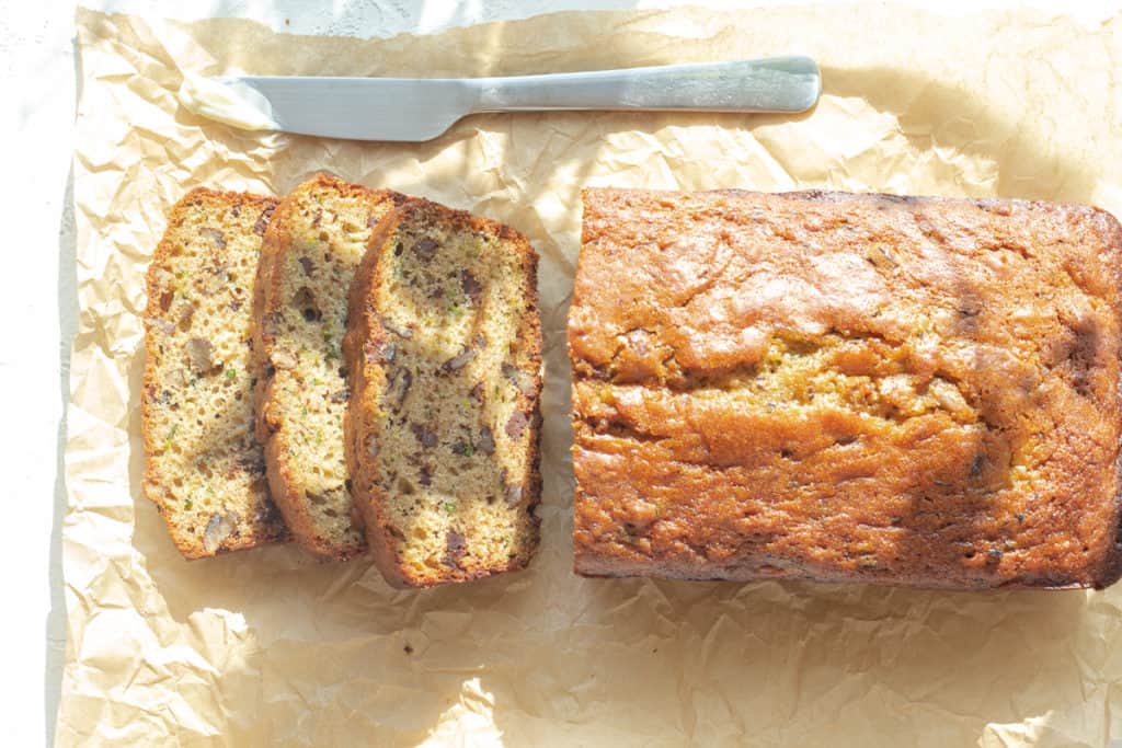 zucchini bread with chocolate chips and pecans sliced on parchment paper