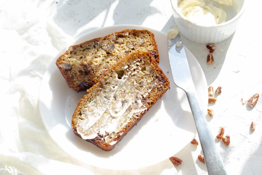 zucchini bread slice with butter on a round plate