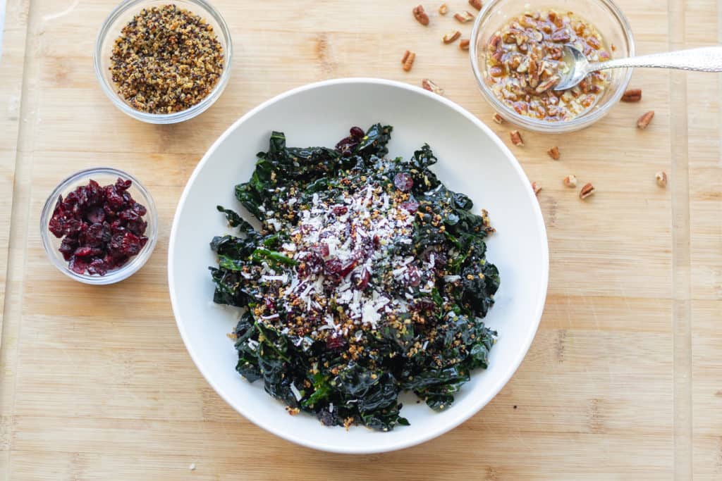 Kale salad bowl with a side of pecan vinagrette and dried cranberries