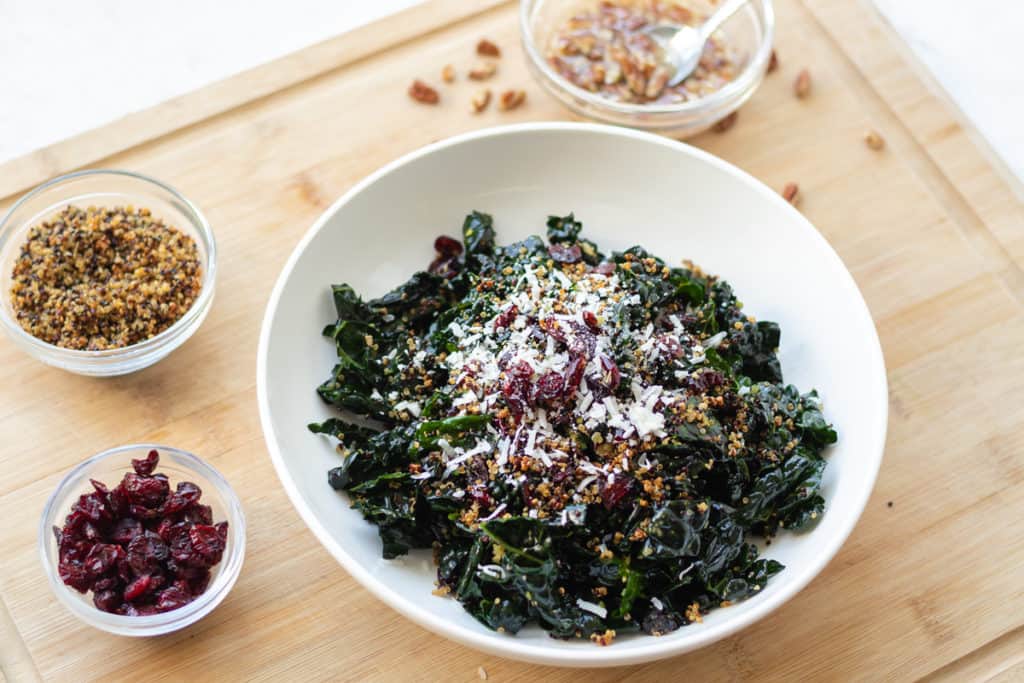 warm kale salad topped with crispy quinoa, dried cranberries and parmesan cheese
