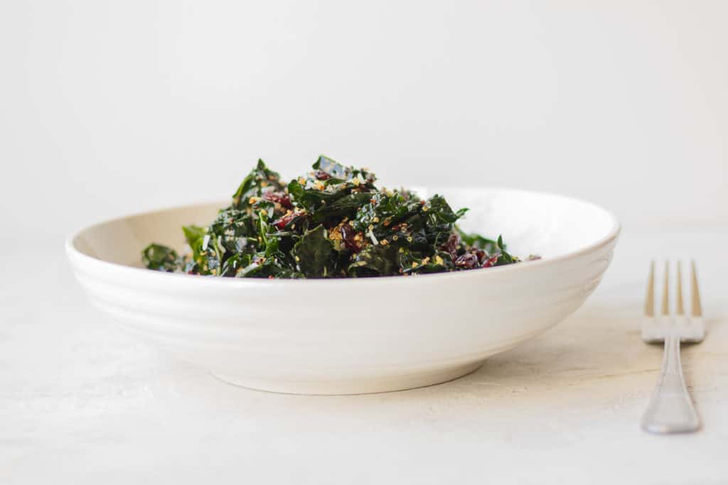 A bowl of warm kale salad with a fork next to it