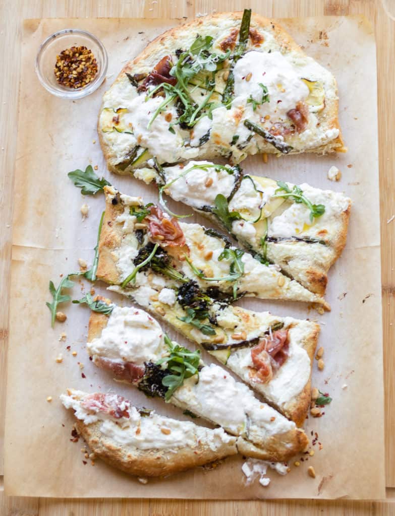 spring pizza topped with seasonal veggies and cut into slices