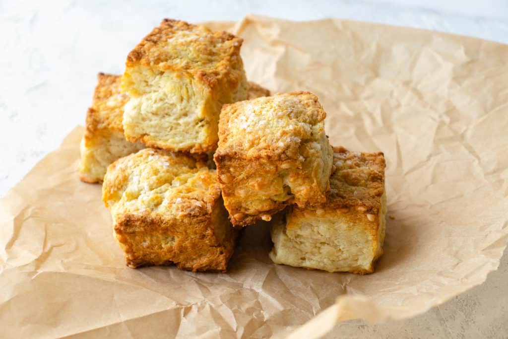 fluffy and tall biscuits stacked on top of each other on parchment paper