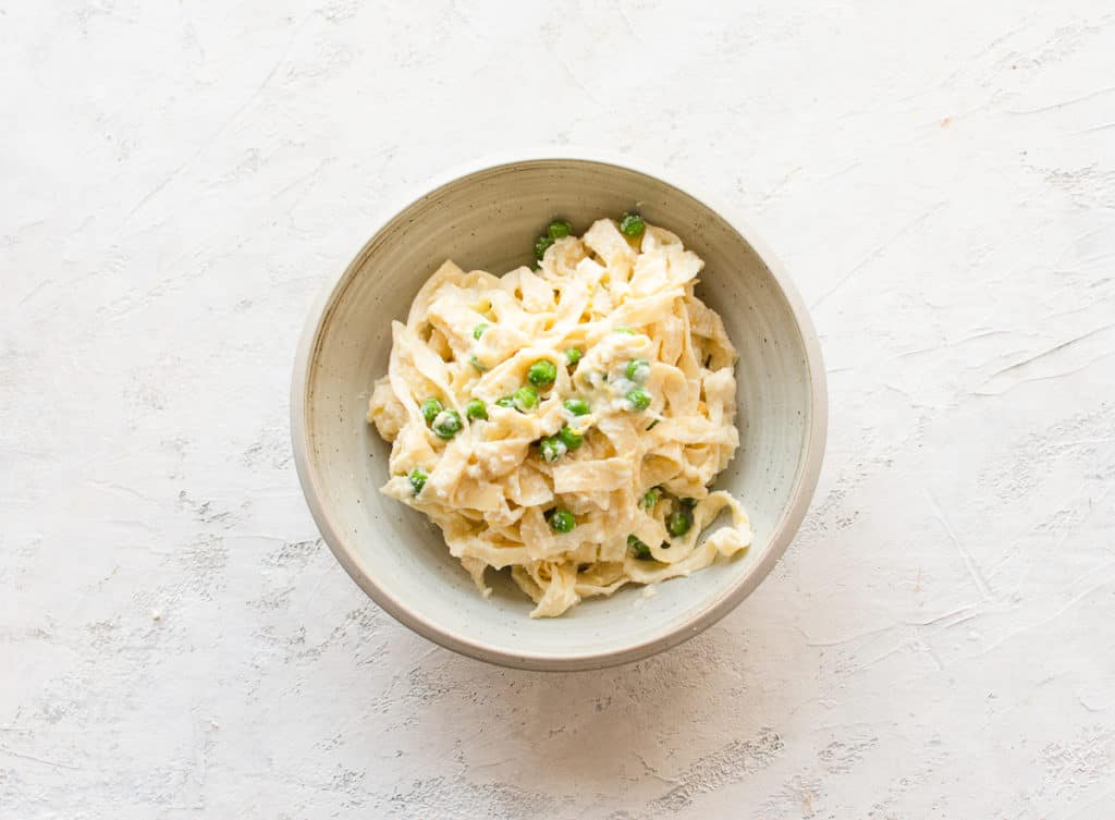 tagliatelle pasta in a bowl with lemon, ricotta, and peas
