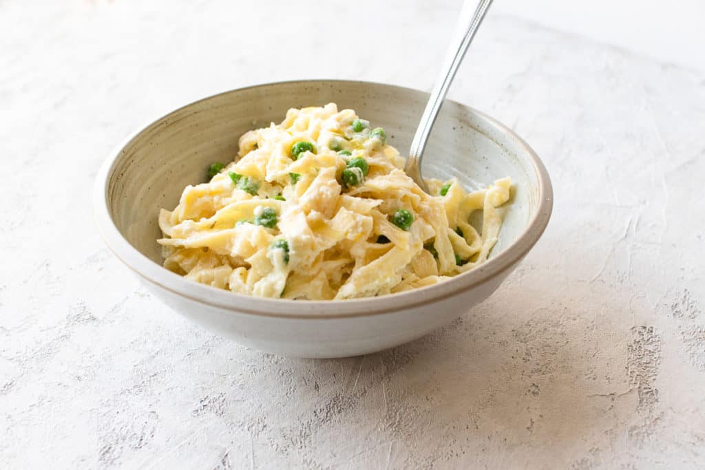 bowl of lemon ricotta pasta with peas with a fork in it