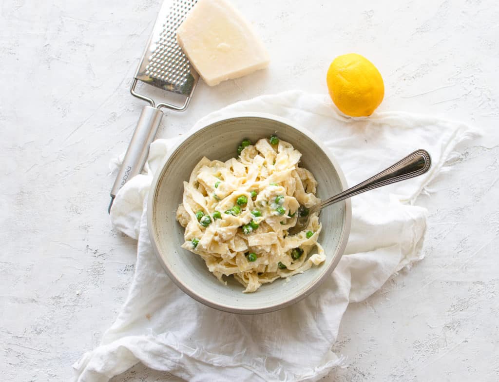 creamy lemon ricotta pasta in a bowl with a side of pecorino cheese