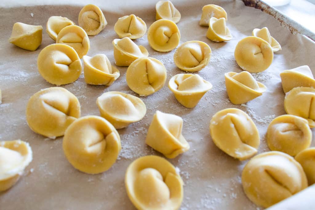tortellini pasta shapes on a parchment lined baking sheet