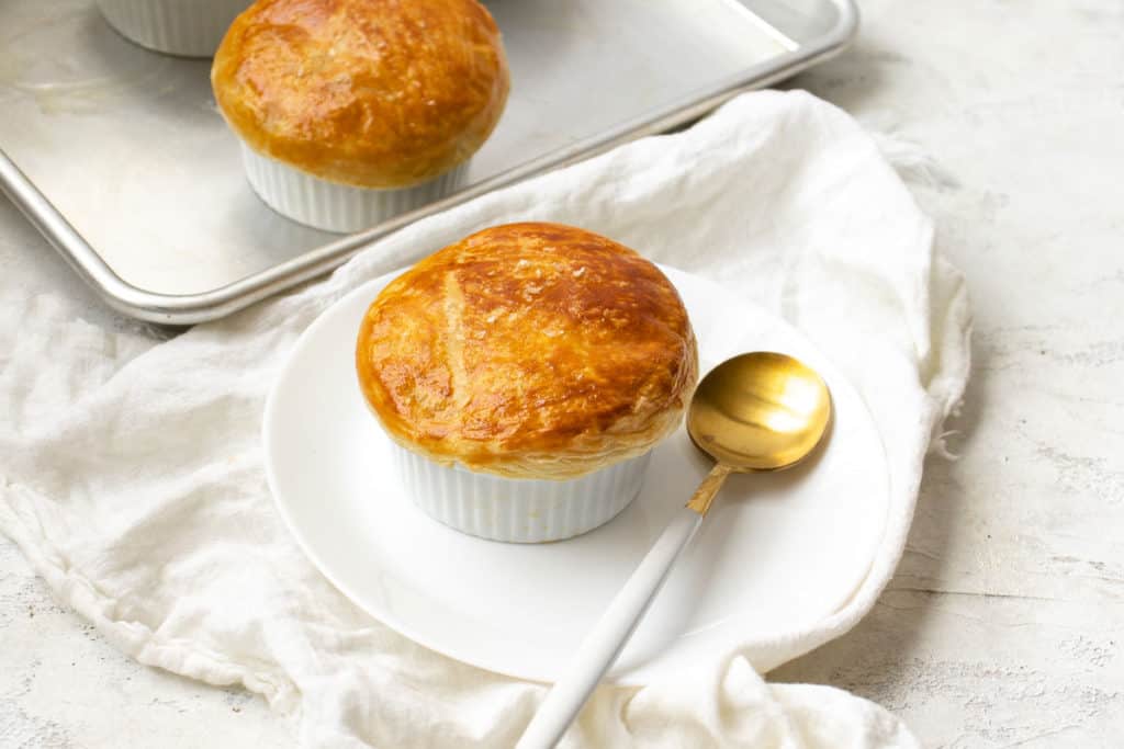 golden brown flaky crust pot pie on a plate with a golden spoon