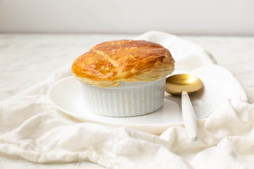 butter chicken pot pie with a golden brown crust on a plate with a golden spoon