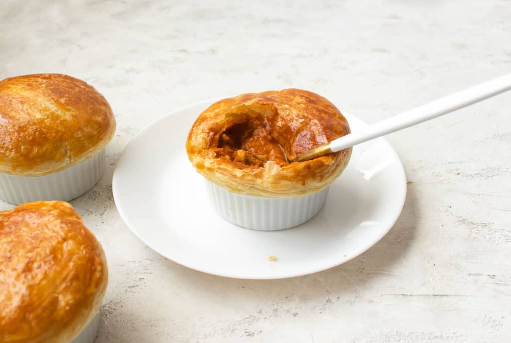 butter chicken pot pie with a spoon in it breaking the crust