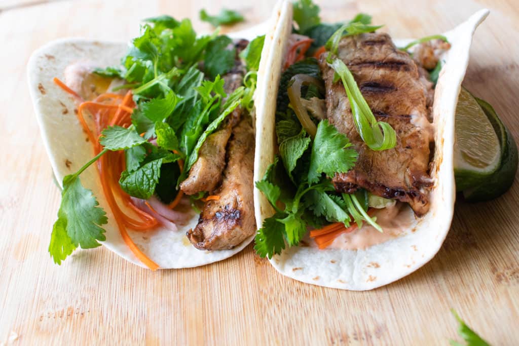 tacos with marinated pork, herbs, pickled vegetables and sriracha aioli