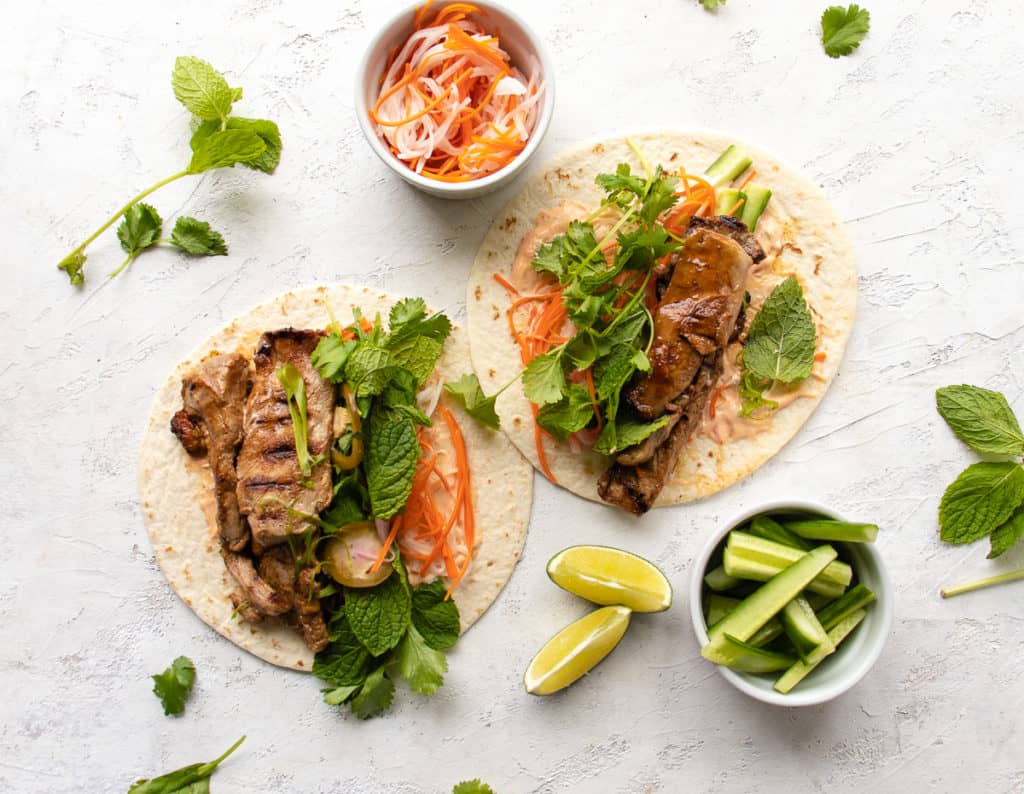 bahn mi tacos with pickled vegetables, herbs, and a side of cucumber sticks
