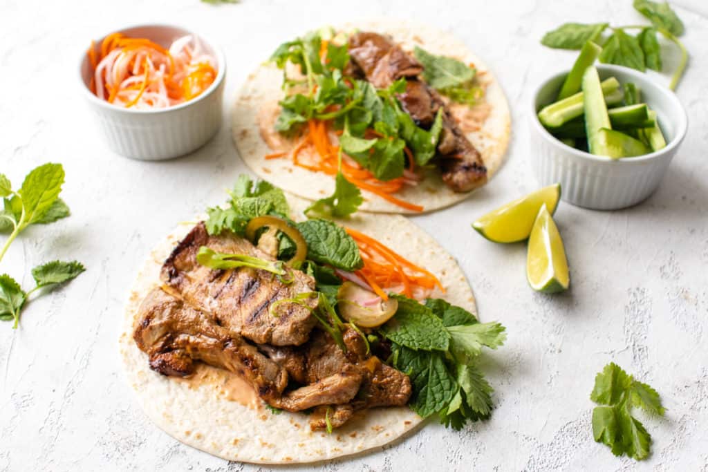 Tacos with marinated pork, veggies and herbs with a side of lime