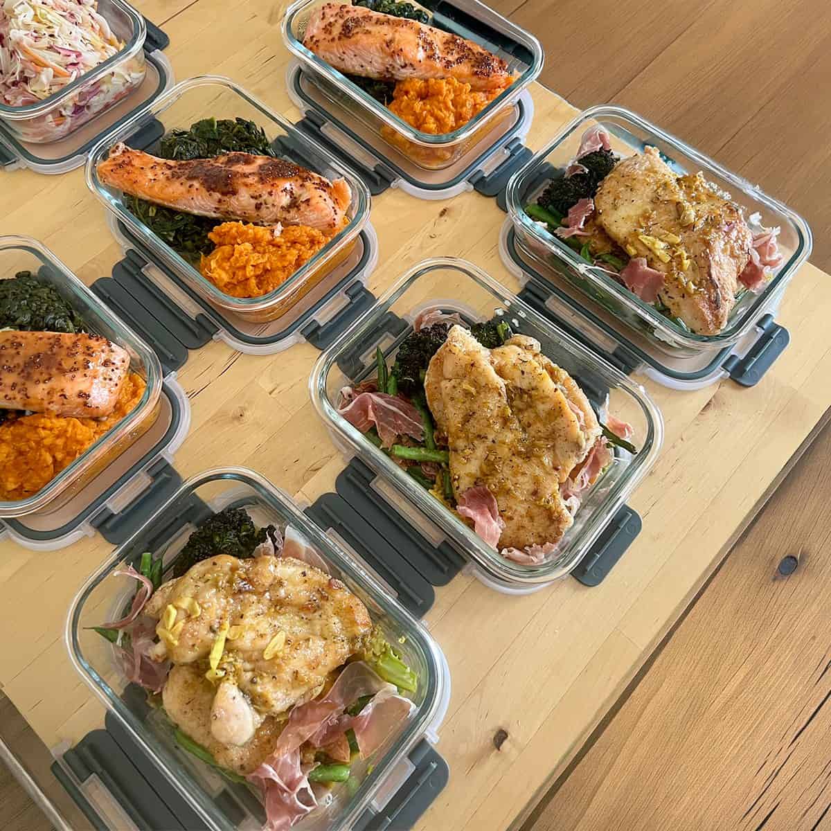 Salmon with sweet potato mash and chicken with prosciutto, portioned into glass meal prep containers