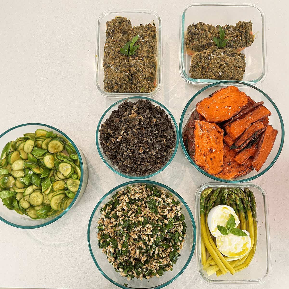 Bright glass bowls of herb-crusted fish, grains, sweet potato and vegetables portioned for the week