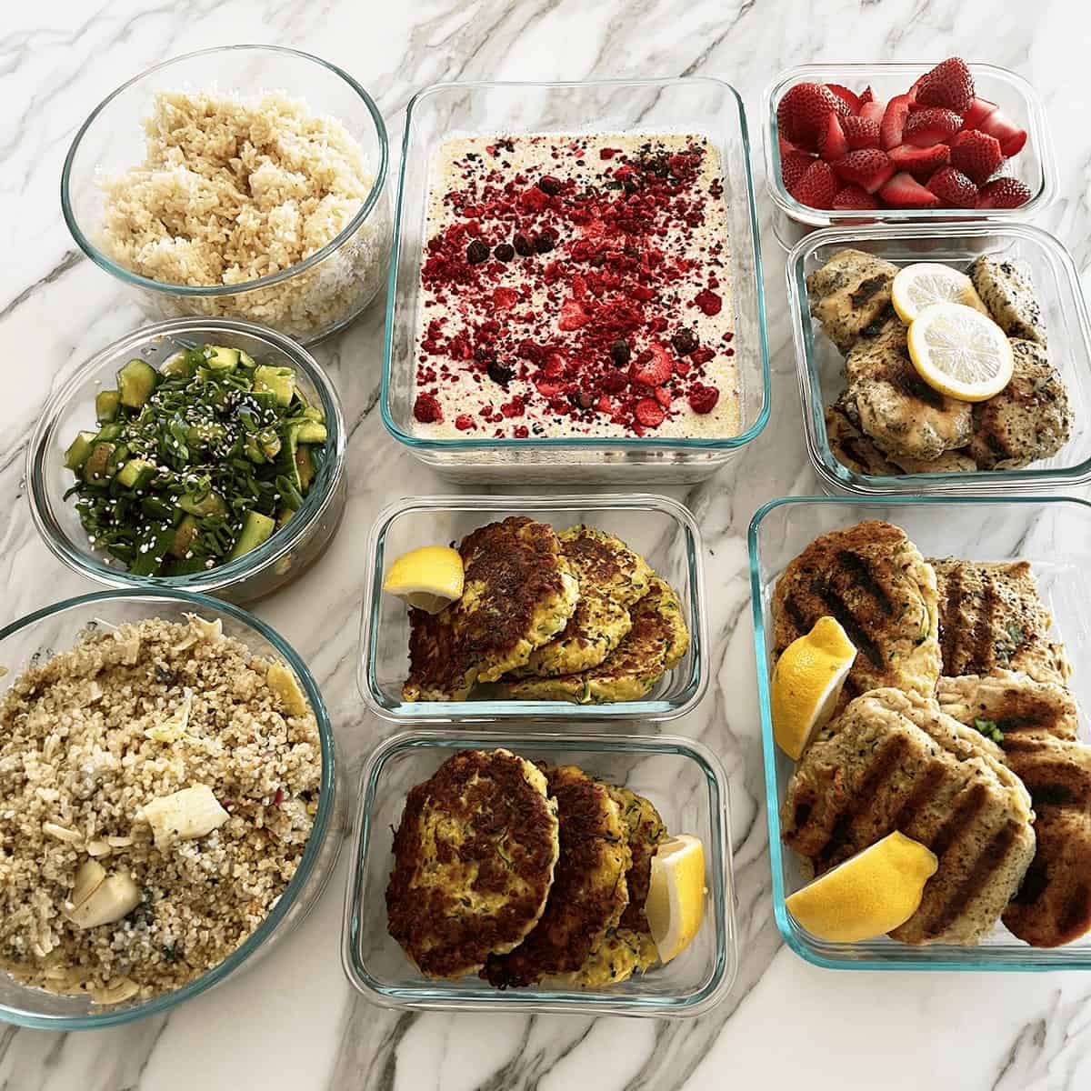Glass containers of breakfasts, fruit, grains and grilled mains from one meal prep day