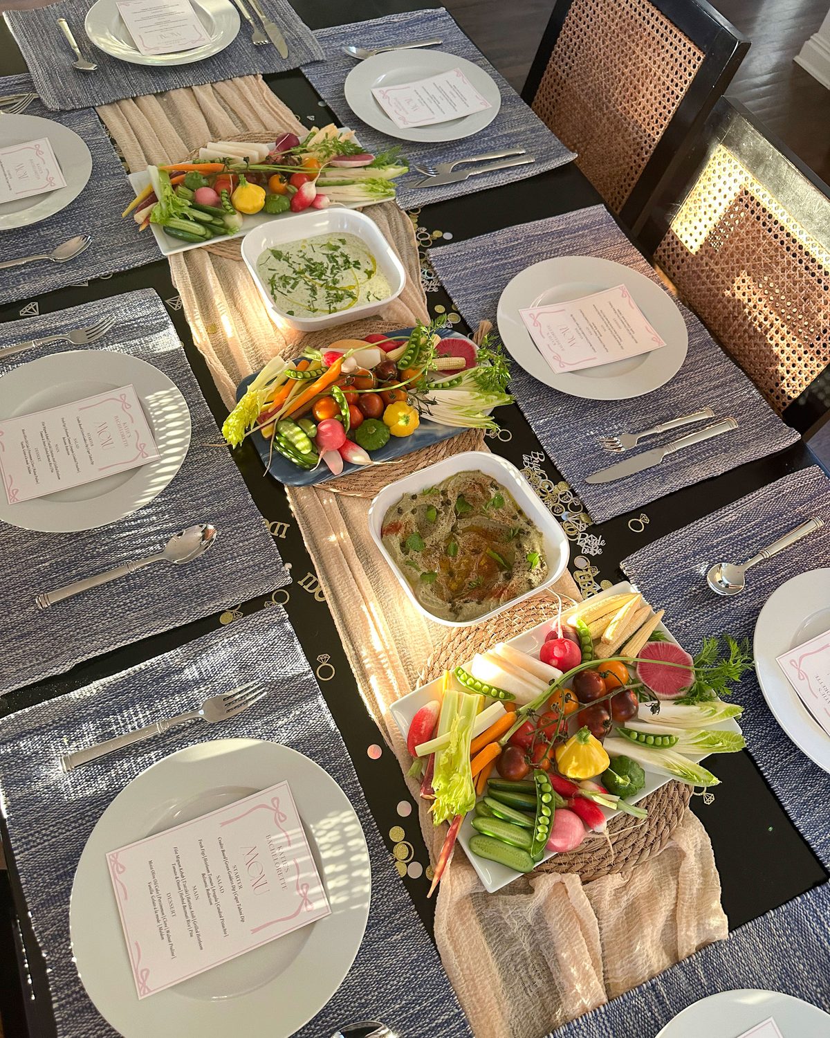 Family-style dinner party table set with crudites, dips and printed menus at each place