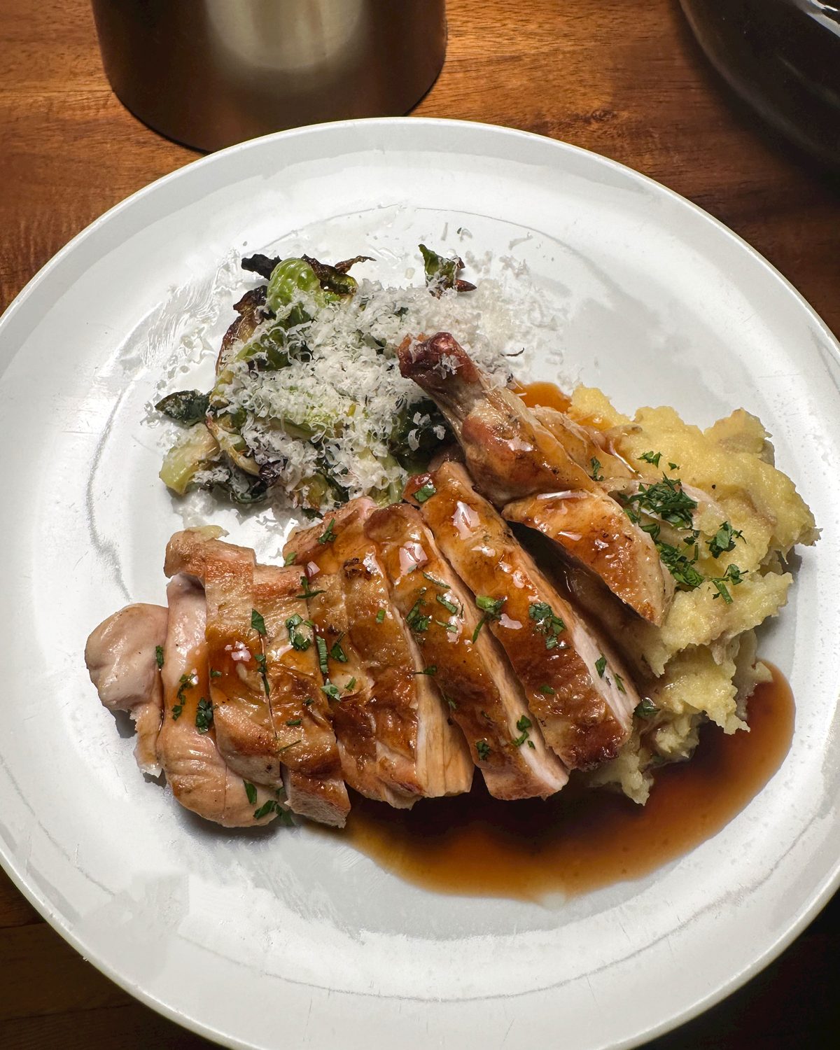 Plated roast chicken with jus, mashed potatoes and Parmesan Brussels sprouts