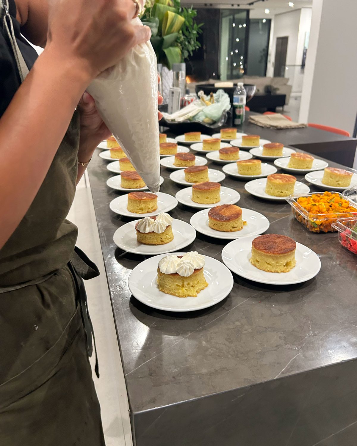Private chef piping cream onto rows of plated desserts for a dinner party