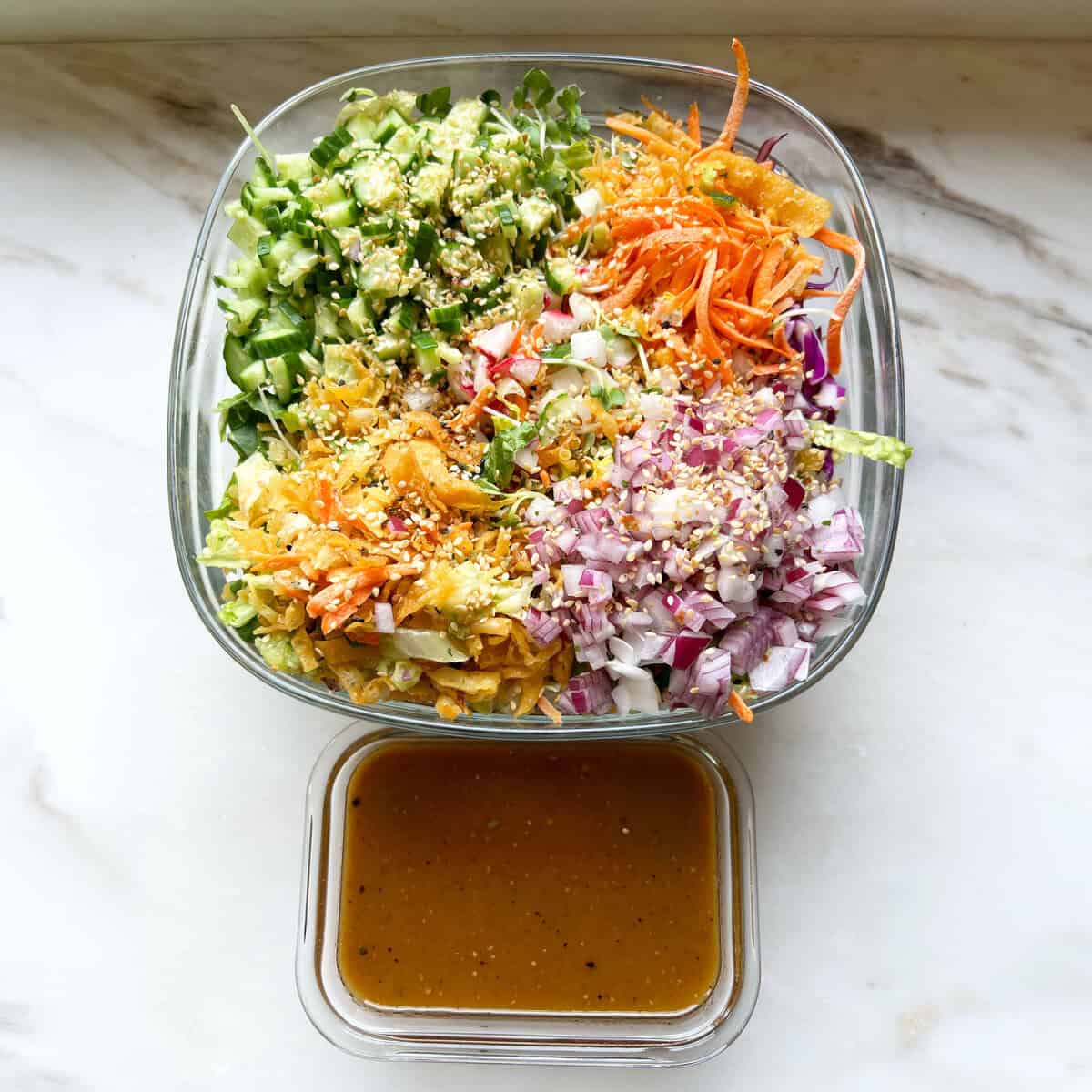 A chopped vegetable salad with sesame and a separate container of dressing