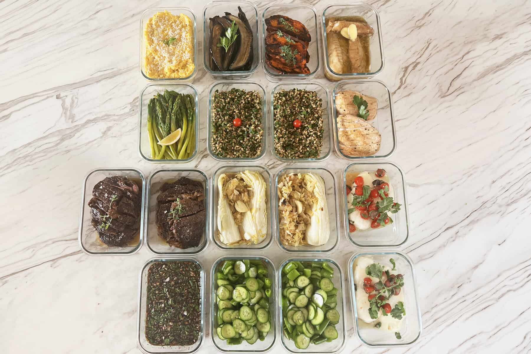 A full week of private chef meals portioned in glass containers on a marble counter